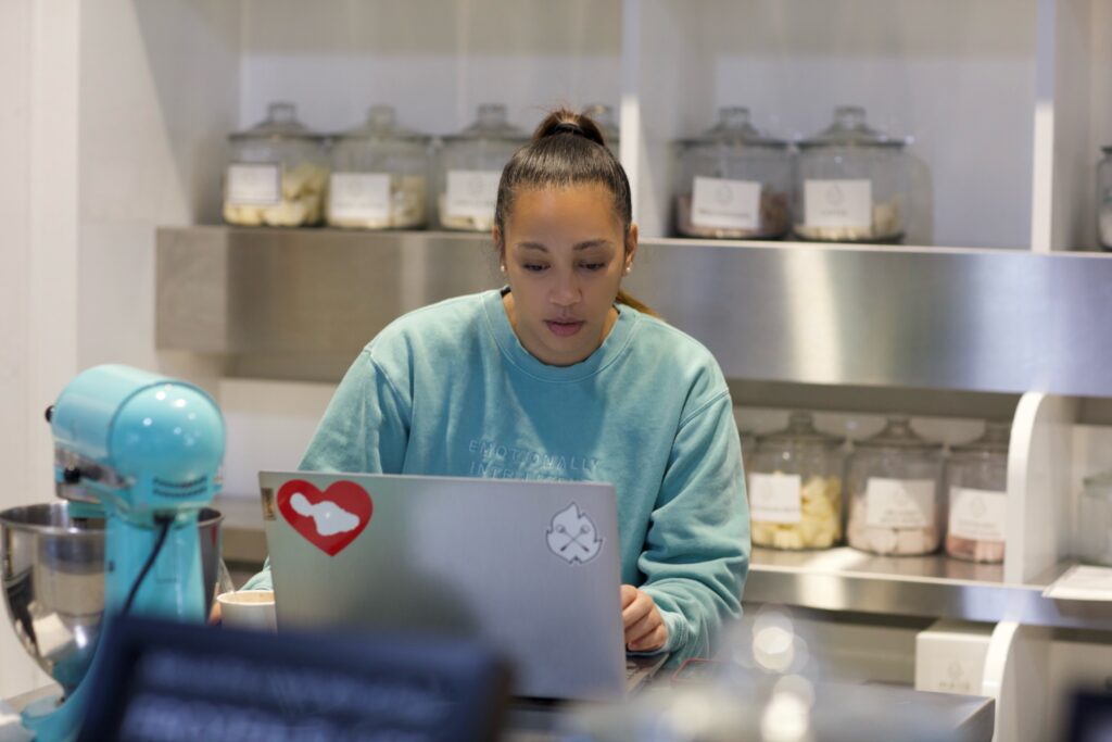 Entrepreneur working on laptop in Emotionally Intelligent branded sweatshirt.