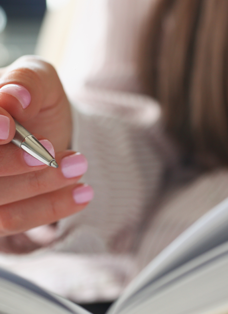 woman with manicured nails journaling about self-awareness